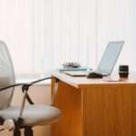 A tranquil modern home office featuring a wooden desk, ergonomic chair, and soft natural light.