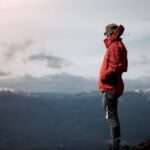 Adventurer in red jacket enjoying the breathtaking view over Tongariro National Park's mountains.